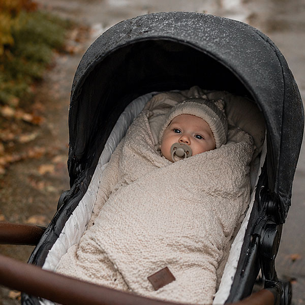 Baby in een wikkeldeken buiten in een kinderwagen - slimmetkleintjes.nl